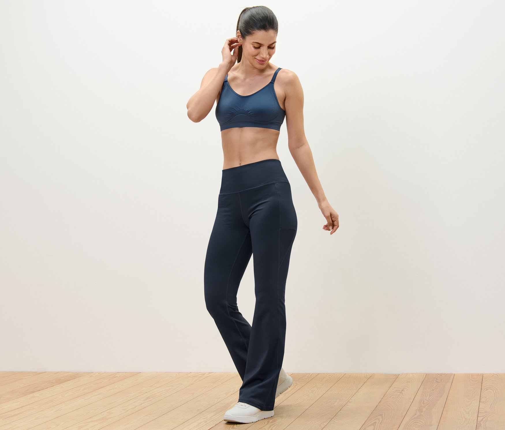 Frau trägt eine Sporthose und einen Sport-BH.