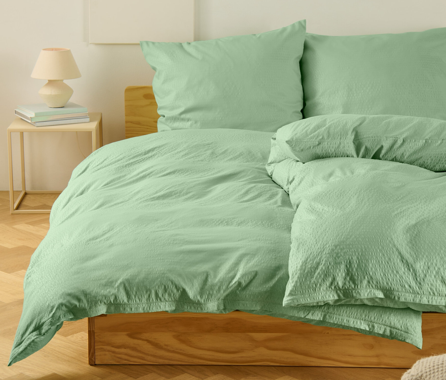 Grüne Seersucker-Bettwäsche in Normalgröße und Übergröße auf einem Bett.