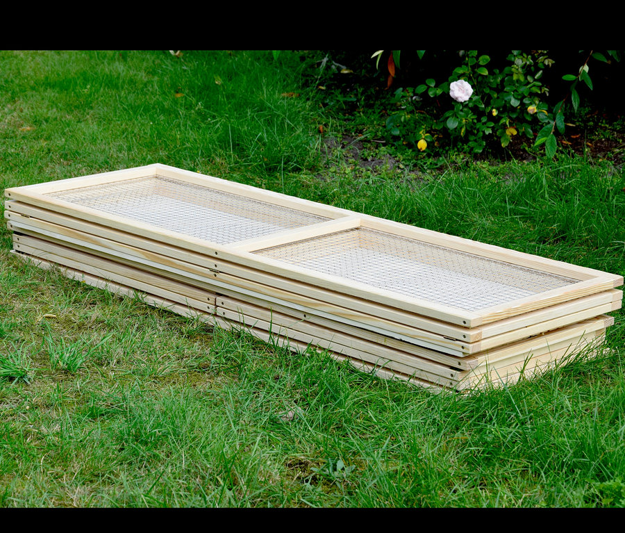 Zusammengelegte Dobar Freilaufgehege-Elemente liegen auf einer Wiese.