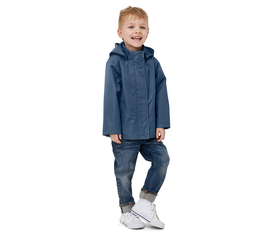 Ein Junge steht und trägt eine blaue Kleinkind-3-in-1-Outdoorjacke, Jeans und Turnschuhe.