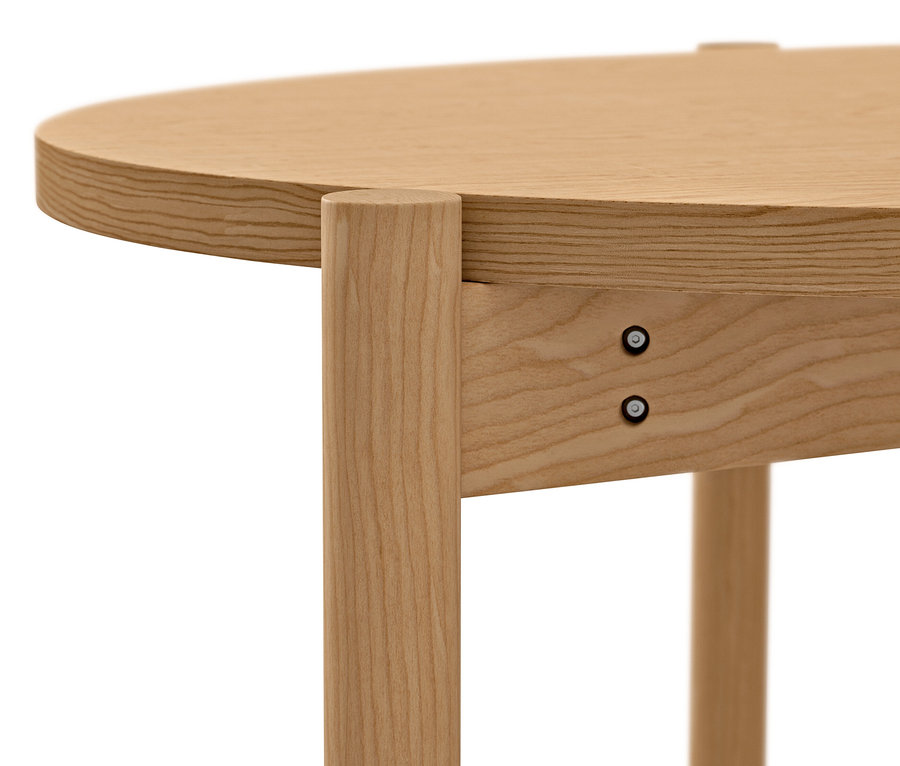 Detailansicht eines runden Couchtisches aus hellem Holz mit sichtbaren Schrauben.