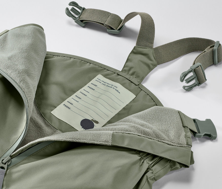 Detailaufnahme einer olivgrünen Kleinkind-Regenhose mit Latz, Fleece-Futter und Namensschild.