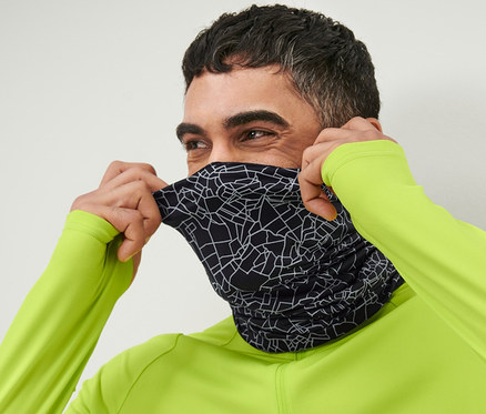 Mann zieht sich ein schwarzes, reflektierendes Multifunktionstuch über das Gesicht.