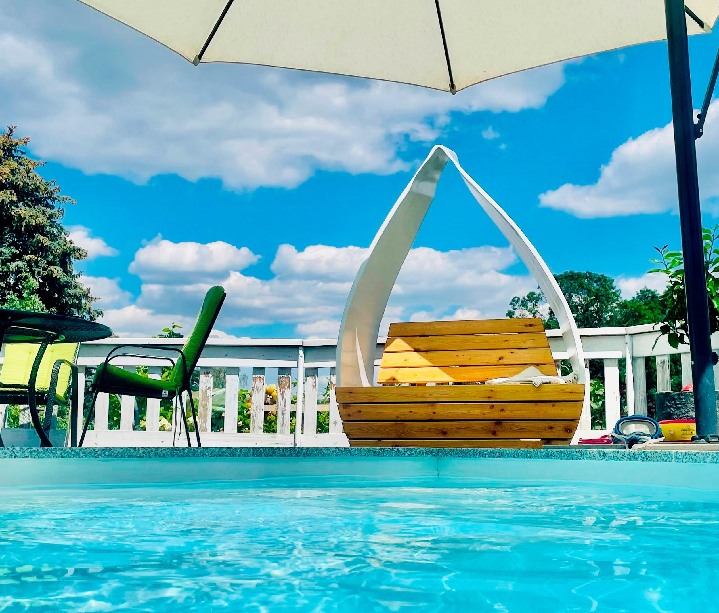 Am Pool stehen ein Tisch mit Stühlen und eine Wings for Living Sitzbank »San Francisco Twin«.