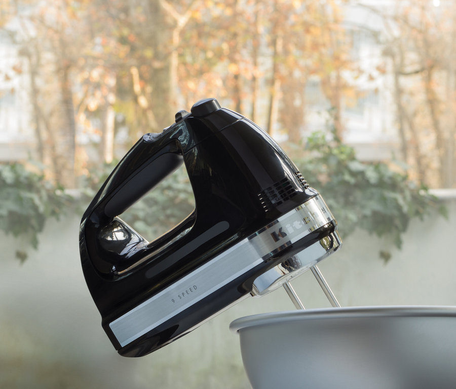 Schwarzer KitchenAid Handmixer über einer grauen Schüssel.