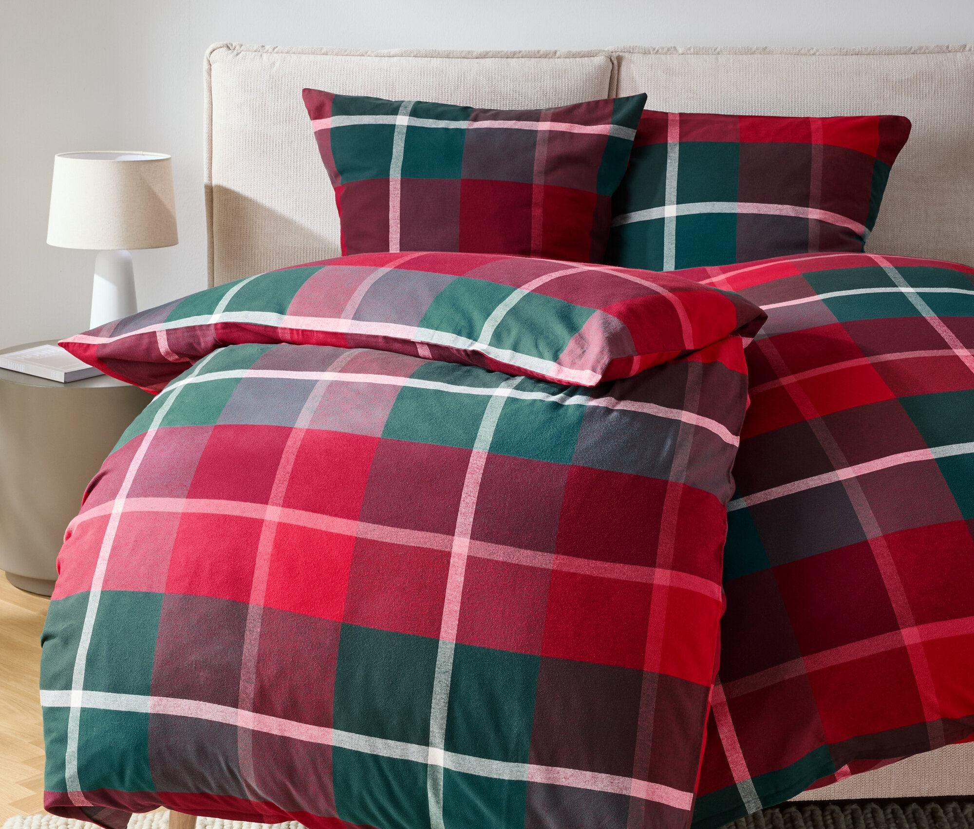 Rot-grün karierte Bettwäsche auf einem Bett mit Kissen.