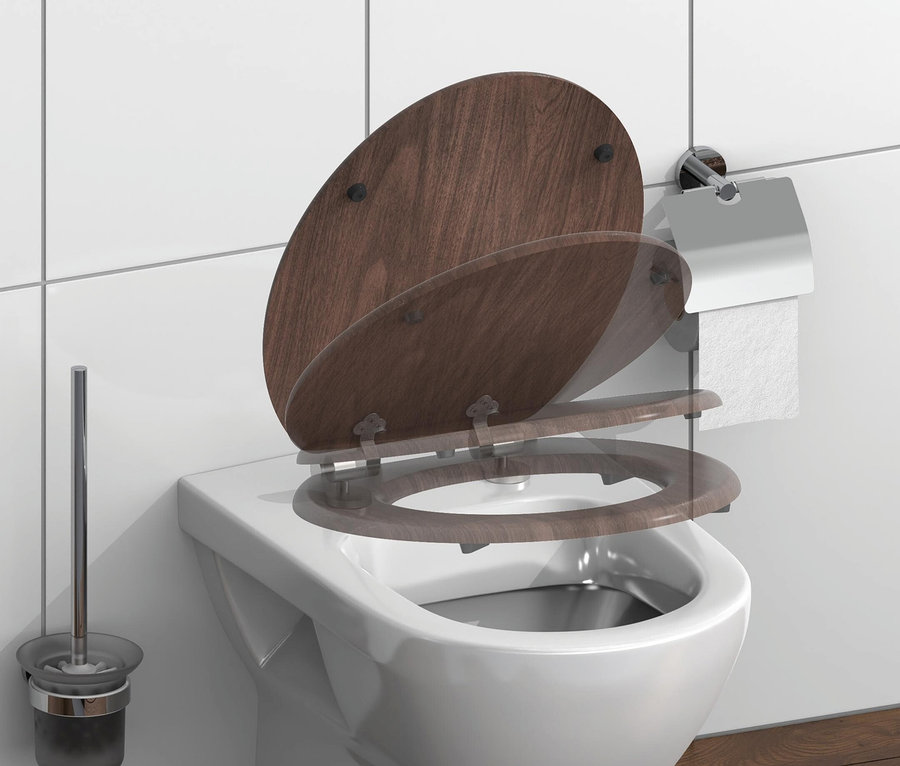 Weiße Toilette mit hochgeklapptem braunen Holzdeckel. An der Wand befinden sich ein Toilettenpapierhalter und neben der Toilette eine Toilettenbürste.