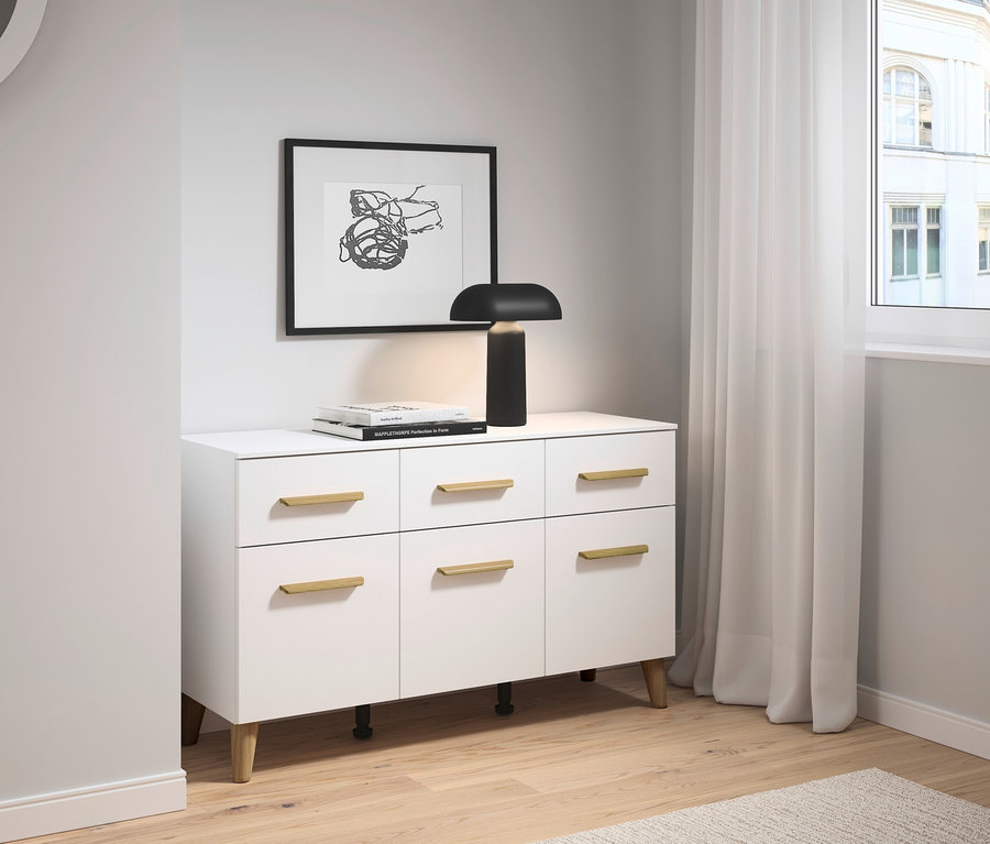 Weißes Sideboard mit sechs Schubladen und goldenen Griffen unter einem schwarzen Rahmen mit Kunstwerk.