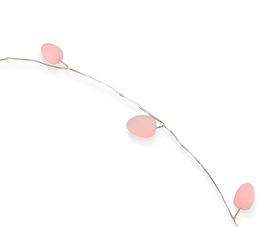 Nahaufnahme einer Lichterkette mit drei rosa Eiern an einem dünnen silbernen Draht vor einem weißen Hintergrund.
