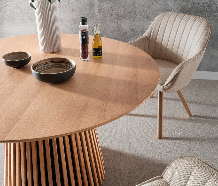 Abgebildet ist ein deVries Esstisch »Oria« aus Natur Oak, rund, 120 cm, mit beigen deVries Esssessel »Matera«.