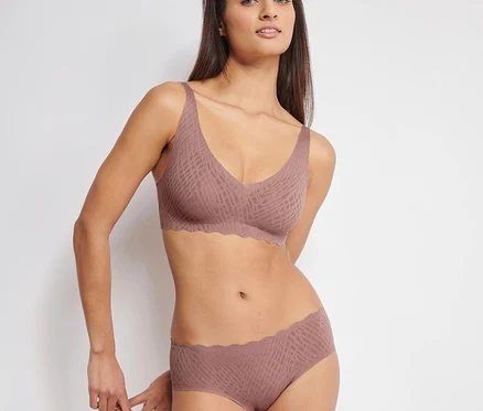 Frau trägt einen kakaofarbenen sloggi ZERO Feel Bliss Soft Bra und passende Höschen mit Muster und Wellenkante.