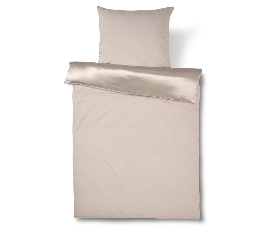 Beige Bettwäsche mit Kissen liegt auf einem weißen Hintergrund.