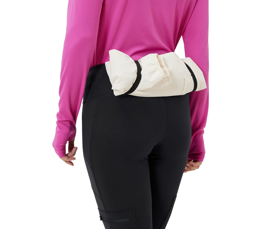 Frau trägt schwarze Outdoor-Tight und eine cremefarbene Jacke um die Taille.