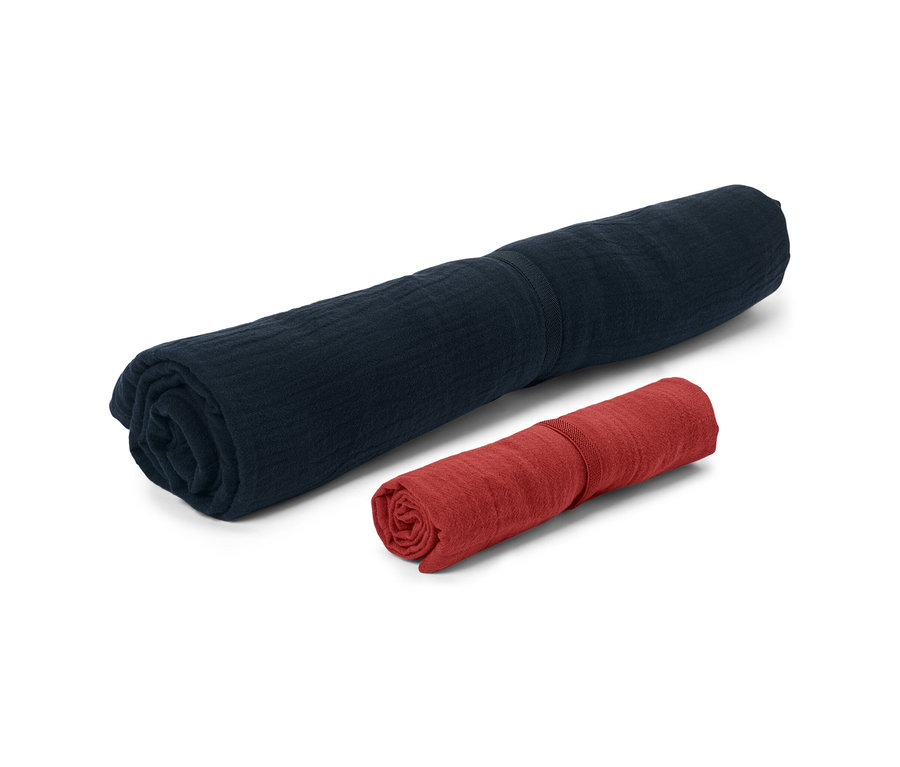 Zwei zusammengerollte Musselin-Handtücher, eines marineblau und eines rot.