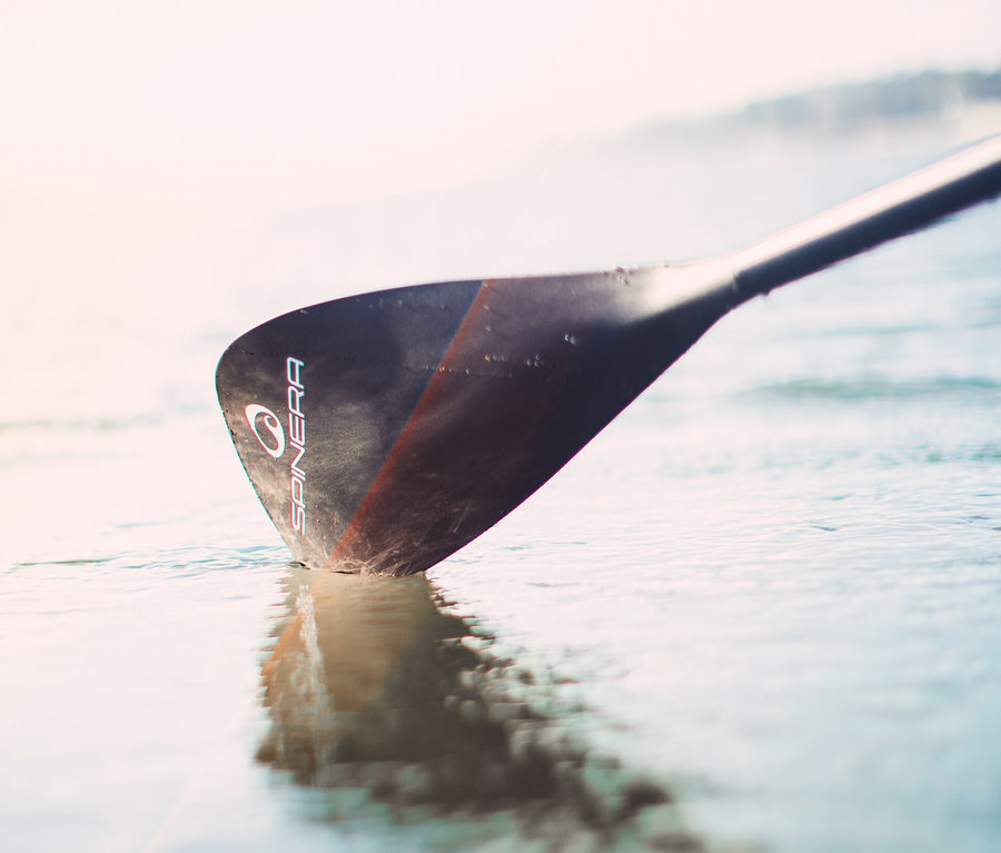 Das Blatt des Spinera Classic Alu SUP Paddels berührt die Wasseroberfläche.