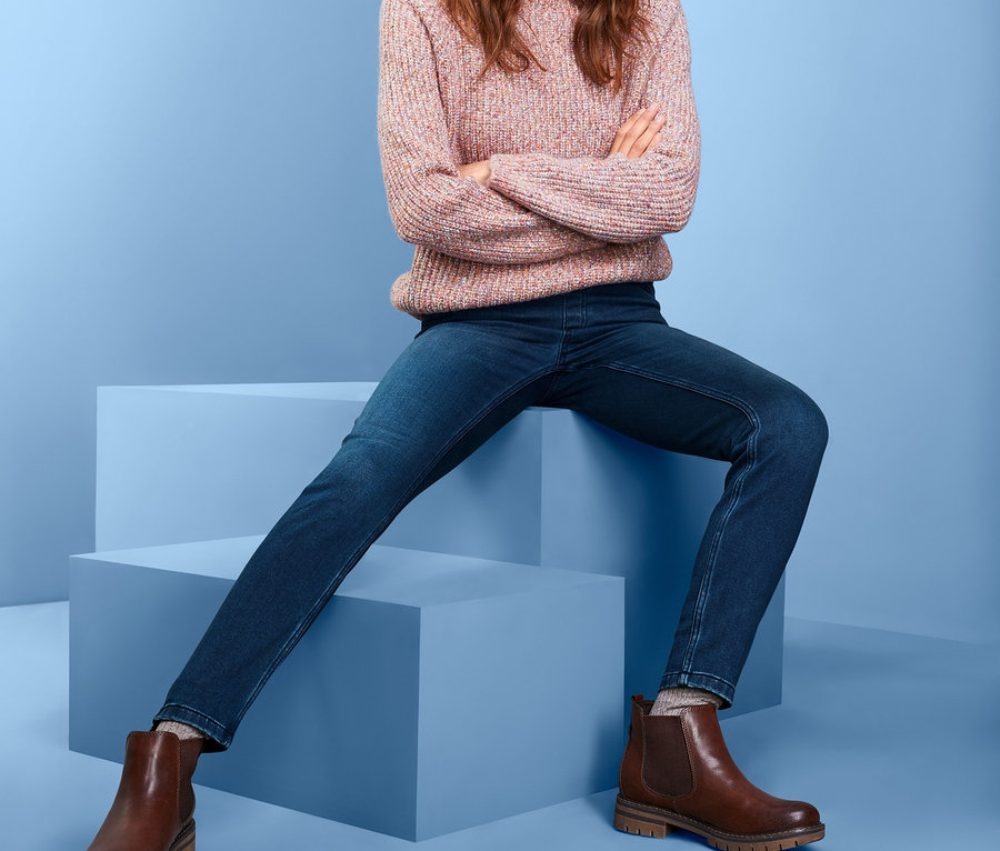 Eine lächelnde Frau sitzt mit gekreuzten Armen auf blauen Würfeln und trägt Thermotreggings.