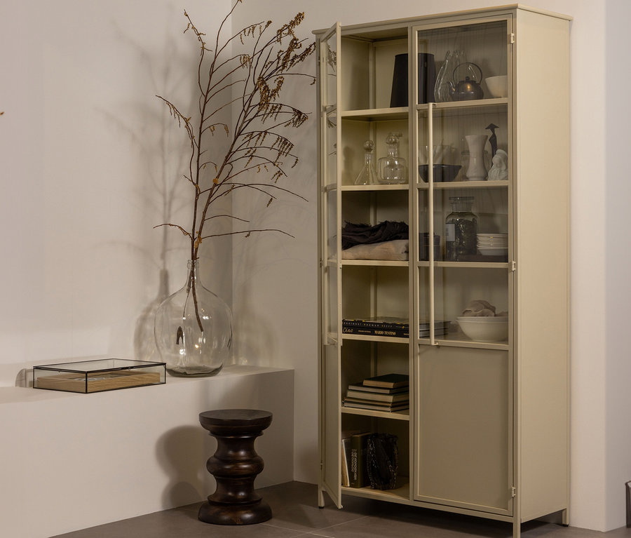 Ein offener, khaki-farbener BePureHome Vitrine "Exhibit" aus Metall steht neben einer Glasvase mit Zweigen.