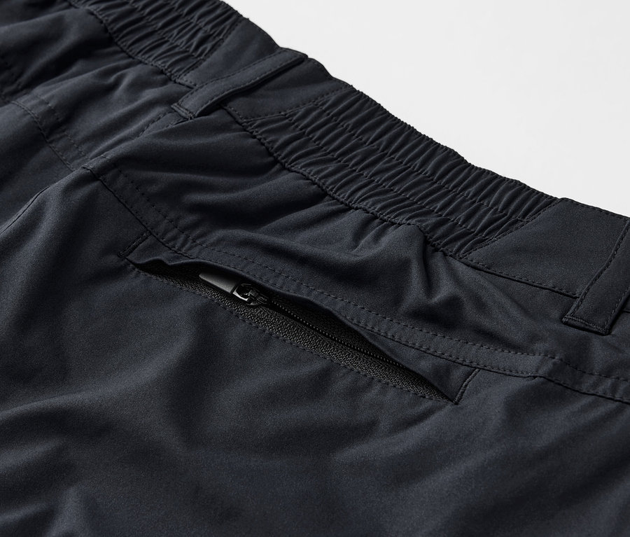 Detailaufnahme einer schwarzen 2-in-1-Funktionshose mit Reißverschlusstasche.