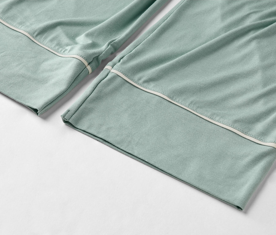Nahaufnahme von hellgrünen Pyjamahosen mit weißer Paspelierung am Saum.