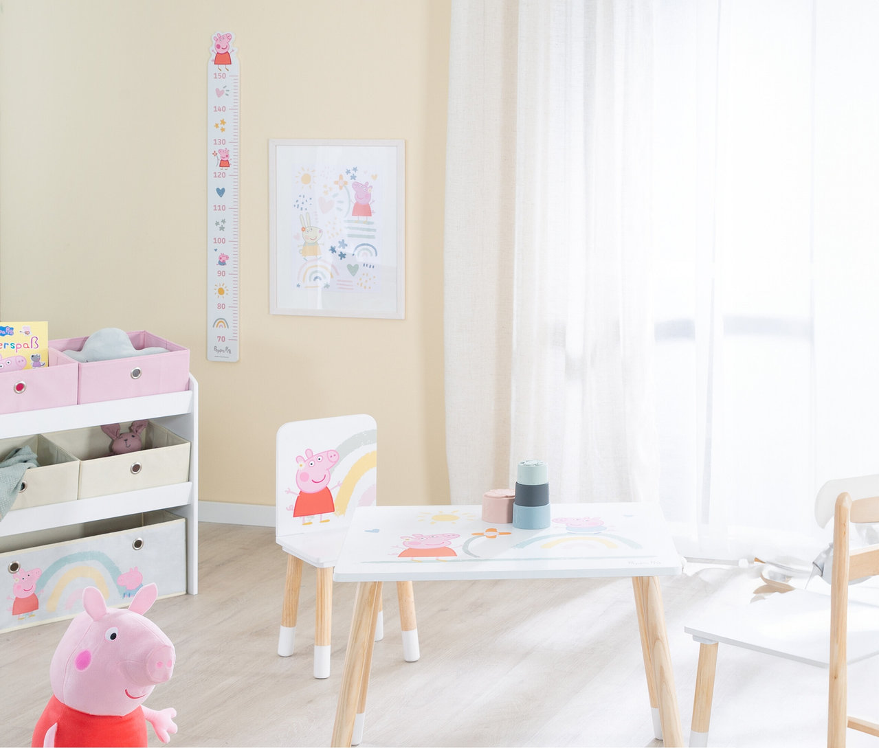 Peppa Pig Stofftier steht vor einem Regal mit Aufbewahrungsboxen, einem Tisch und Stühlen in einem Kinderzimmer.