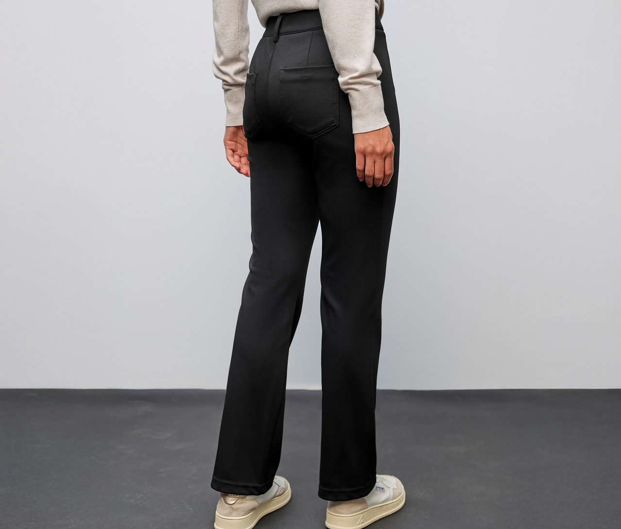 Person von hinten, trägt eine schwarze Street One Bootcut Hose und helle Schuhe.