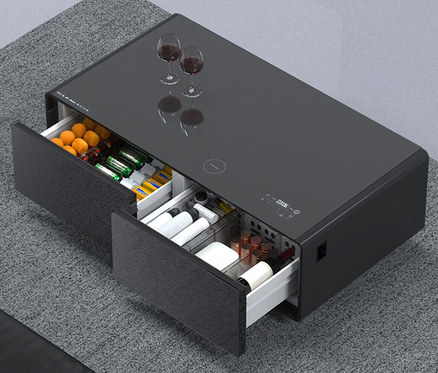 Aufnahme eines Caso Sound & Cool, schwarz, Tisches mit zwei offenen Schubladen, gefüllt mit Getränken und Snacks, auf einem Teppich.