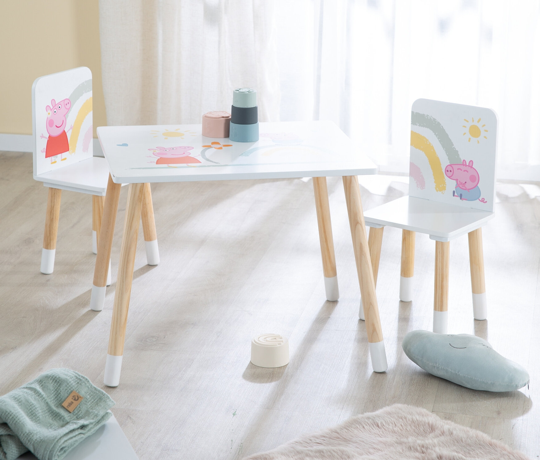 Ein weißer Kindertisch mit zwei Stühlen, dekoriert mit Peppa Pig Motiven, steht in einem hellen Raum.