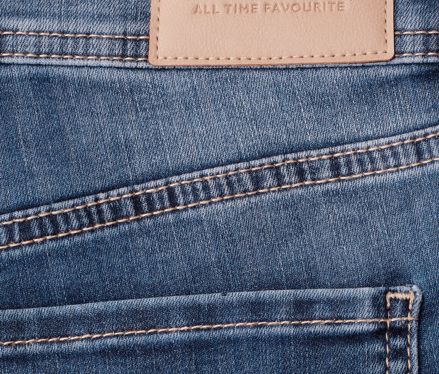 Nahaufnahme einer blauen Street One 7/8-Jeans »Jane« mit beigem Markenetikett und kontrastierenden Nähten.