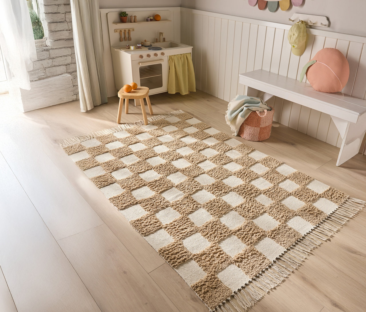 Ein Schachbrettmuster-Teppich liegt auf einem Holzboden in einem Kinderzimmer.