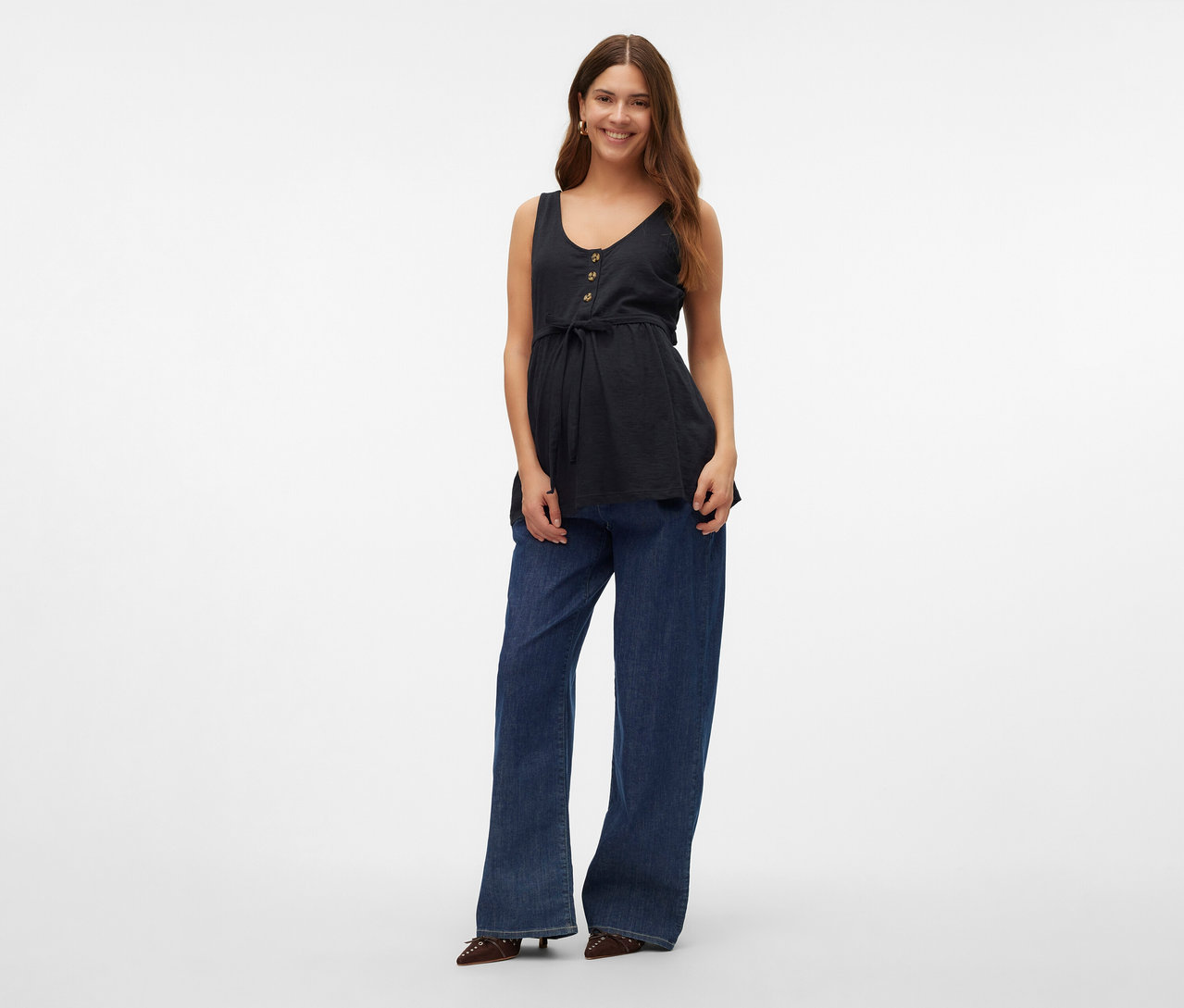 Frau trägt ein MAMALICIOUS Stilltop »MLEVI LIA« mit Knöpfen und Bindeband, dazu Jeans und Schuhe.