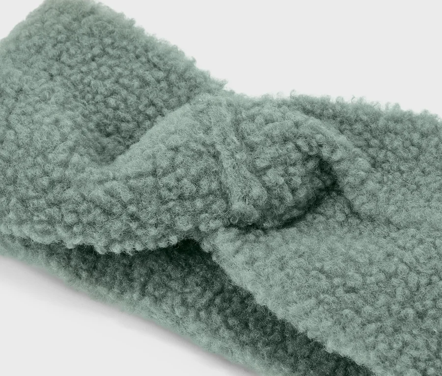 Nahaufnahme eines hellgrünen, verdrehten Stirnbandes aus Teddyplüsch.