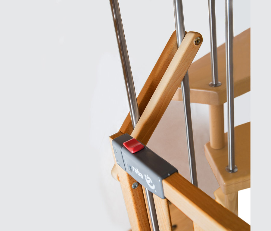Nahaufnahme eines roba Treppenschutzgitters »Safety Up« aus Holz und Metall mit grauem Verschluss und rotem Knopf, an einer Holztreppe montiert.