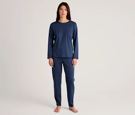 Frau steht barfuß und trägt ein dunkelblaues Langarmshirt mit passender Hose.
