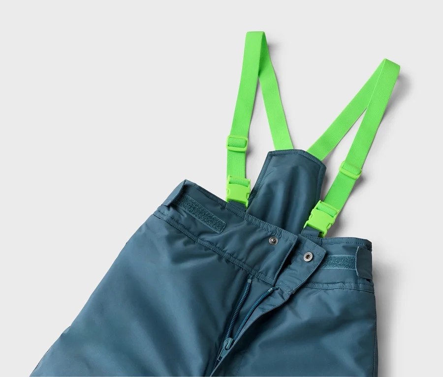 Blaue Skihose mit leuchtend grünen Hosenträgern, die mit Schnallen befestigt sind. Der Reißverschluss der Hose ist leicht geöffnet.