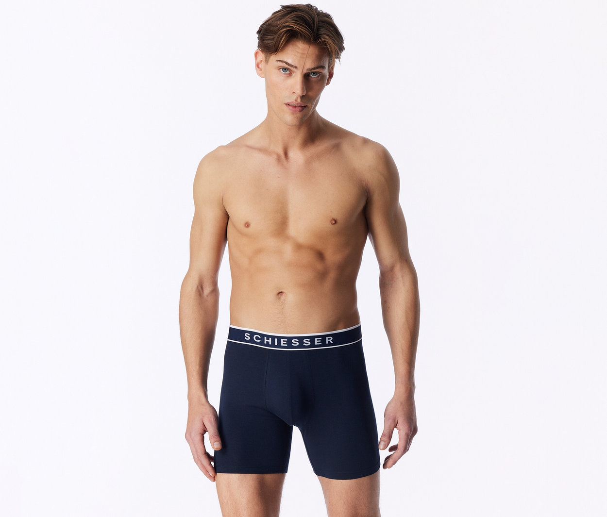 Ein oberkörperfreier Mann trägt dunkelblaue Boxershorts mit weißem SCHIESSER-Bund.