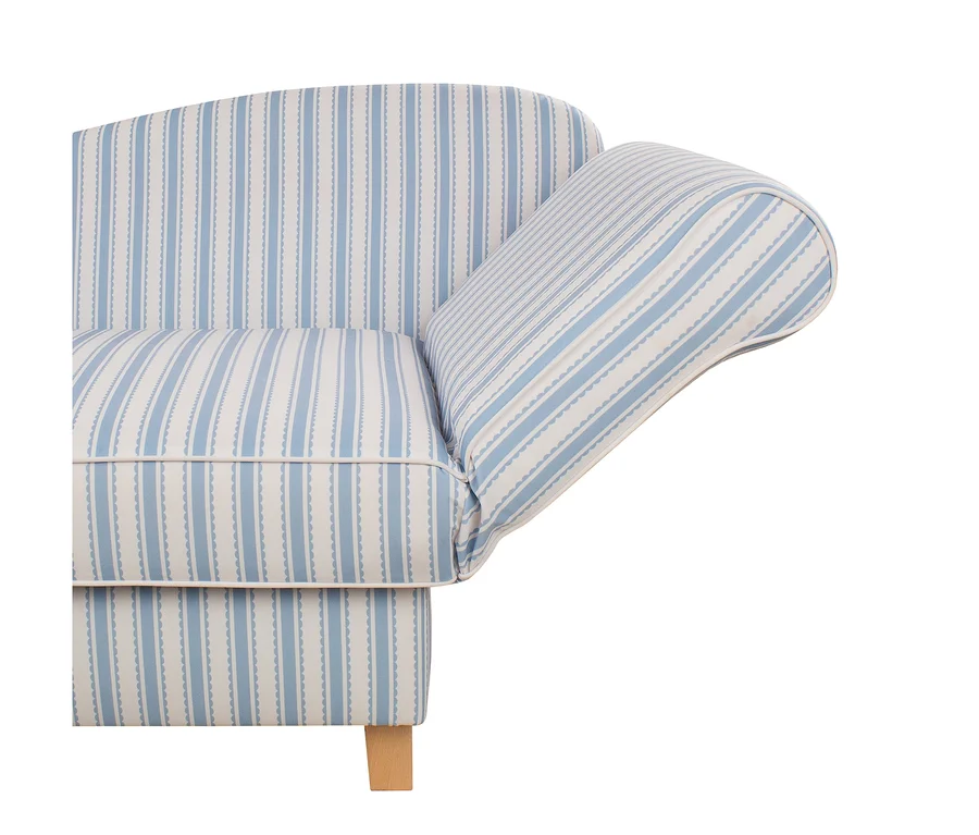 Nahaufnahme eines Sofas, das mit einem blau-weiß gestreiften Stoff bezogen ist, mit Rückenlehne, Sitzkissen und Armlehne. Der Stoff zeigt abwechselnd durchgehende blaue Streifen und blaue Streifen mit Wellenrand auf weißem Hintergrund. Weiße Paspeln umranden die Kissen. Ein heller Holzfuß ist unten sichtbar.