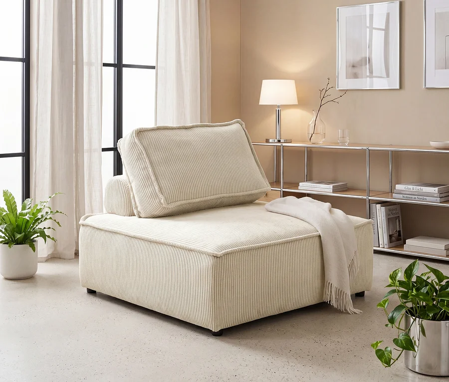 Beiges Cord-Chaiselongue-Element mit einer Decke in einem Wohnzimmer. Großes Fenster mit Vorhängen links, Regal mit Büchern und Deko rechts, flankiert von zwei Topfpflanzen.