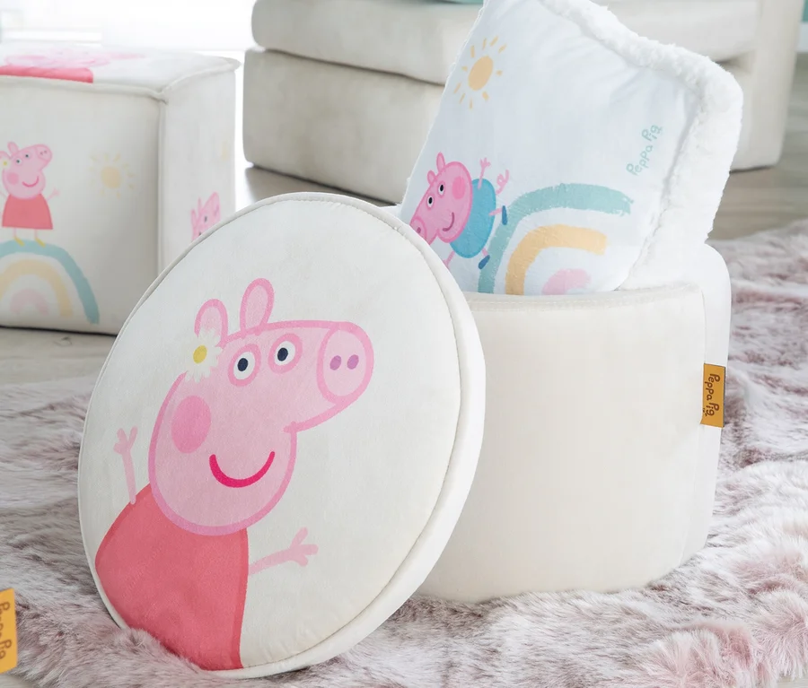 Peppa Pig Motiv auf rundem Kissen neben offenem Hocker und Würfel auf einem Teppich.
