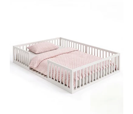 Weißes roba Montessori-Bodenbett (ca. 140 x 200 cm) aus Holz mit Lattenrost und rosa Bettwäsche mit Strukturmuster.
