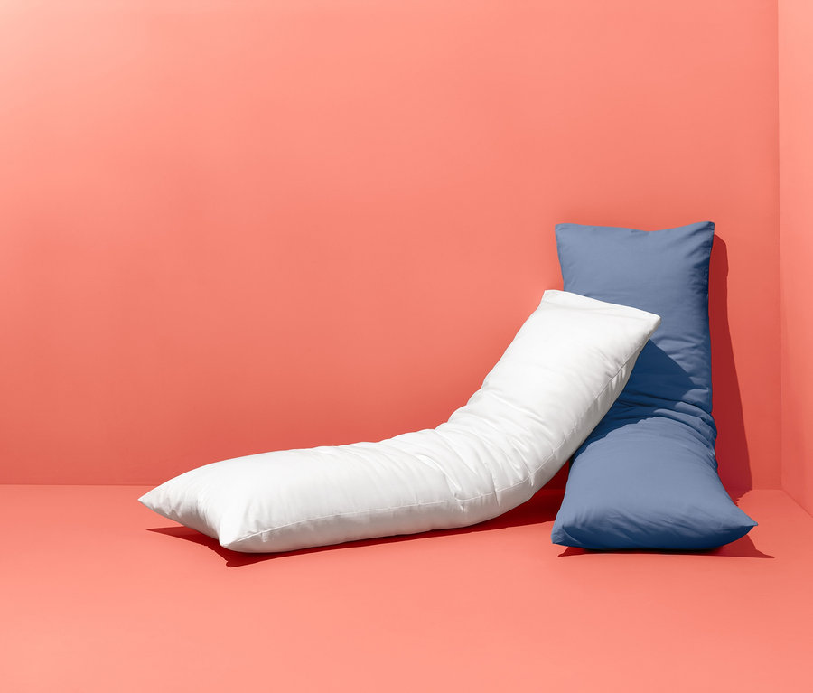 Zwei Renforcé-Seitenschläfer-Kissenbezüge liegen auf dem Boden und lehnen an der Wand.