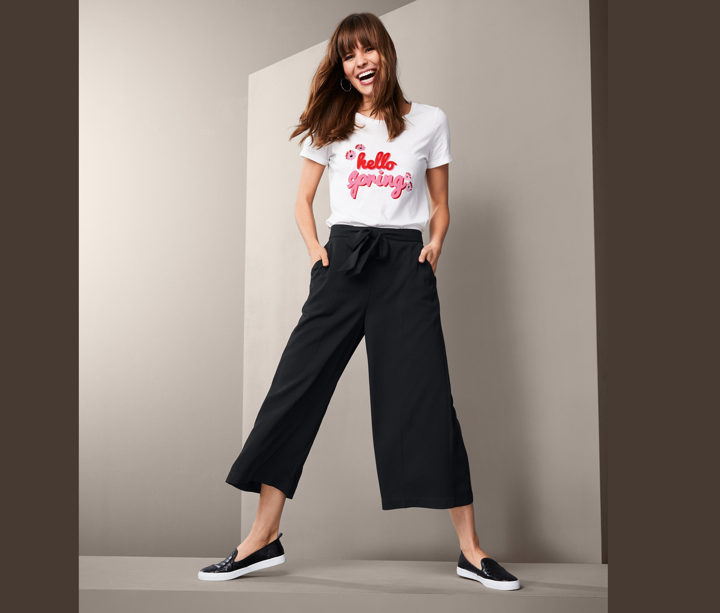 Frau steht mit Händen in den Taschen in einer Culottehose.