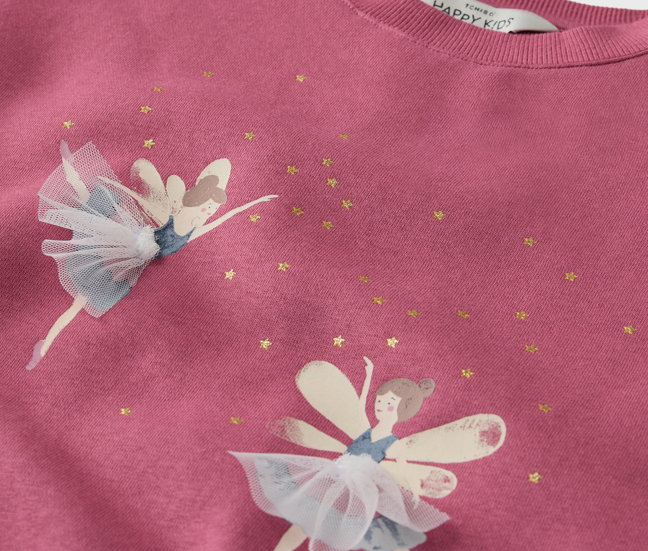 Detailansicht eines rosafarbenen Sweatshirts mit zwei Feen und goldenen Sternen.