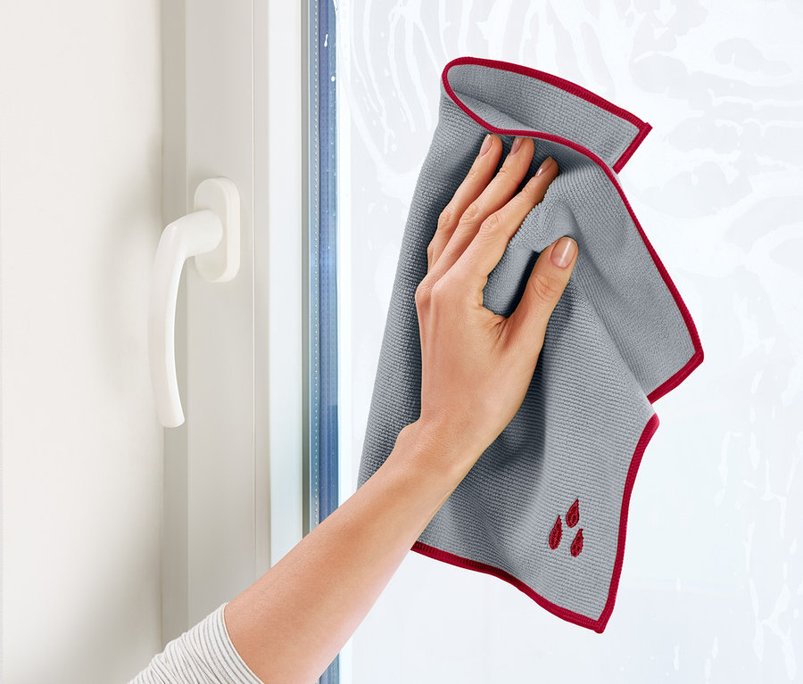 Frau putzt Fenster mit 1 Fenstertuch.
