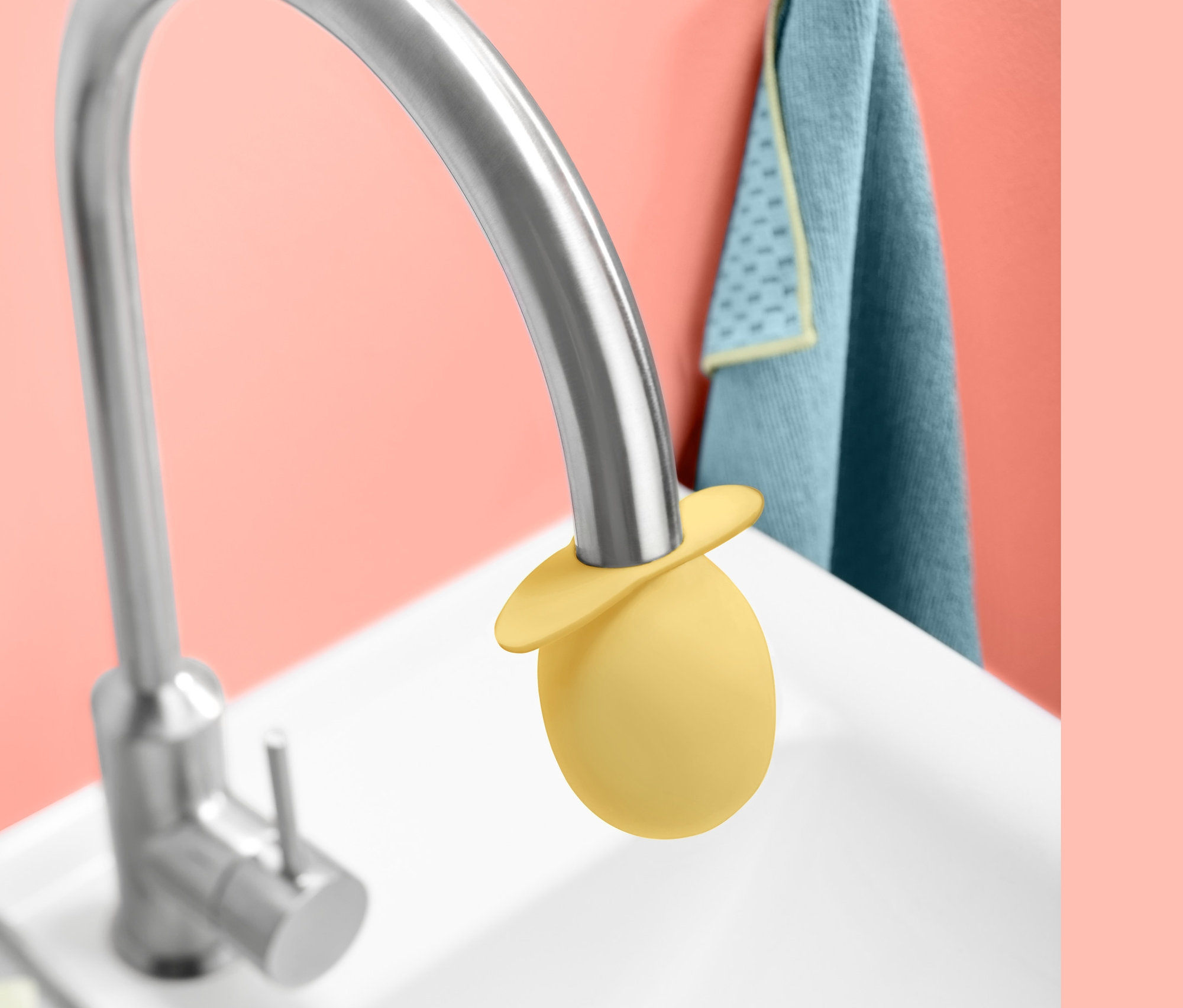 Gelber Wasserhahn-Entkalker-Aufsatz auf einem silbernen Wasserhahn in einem weißen Waschbecken.