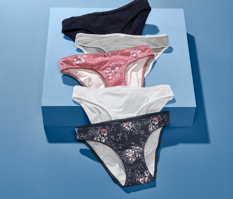 Fünf Slips liegen auf einem blauen Sockel. Sie haben verschiedene Farben und Muster.