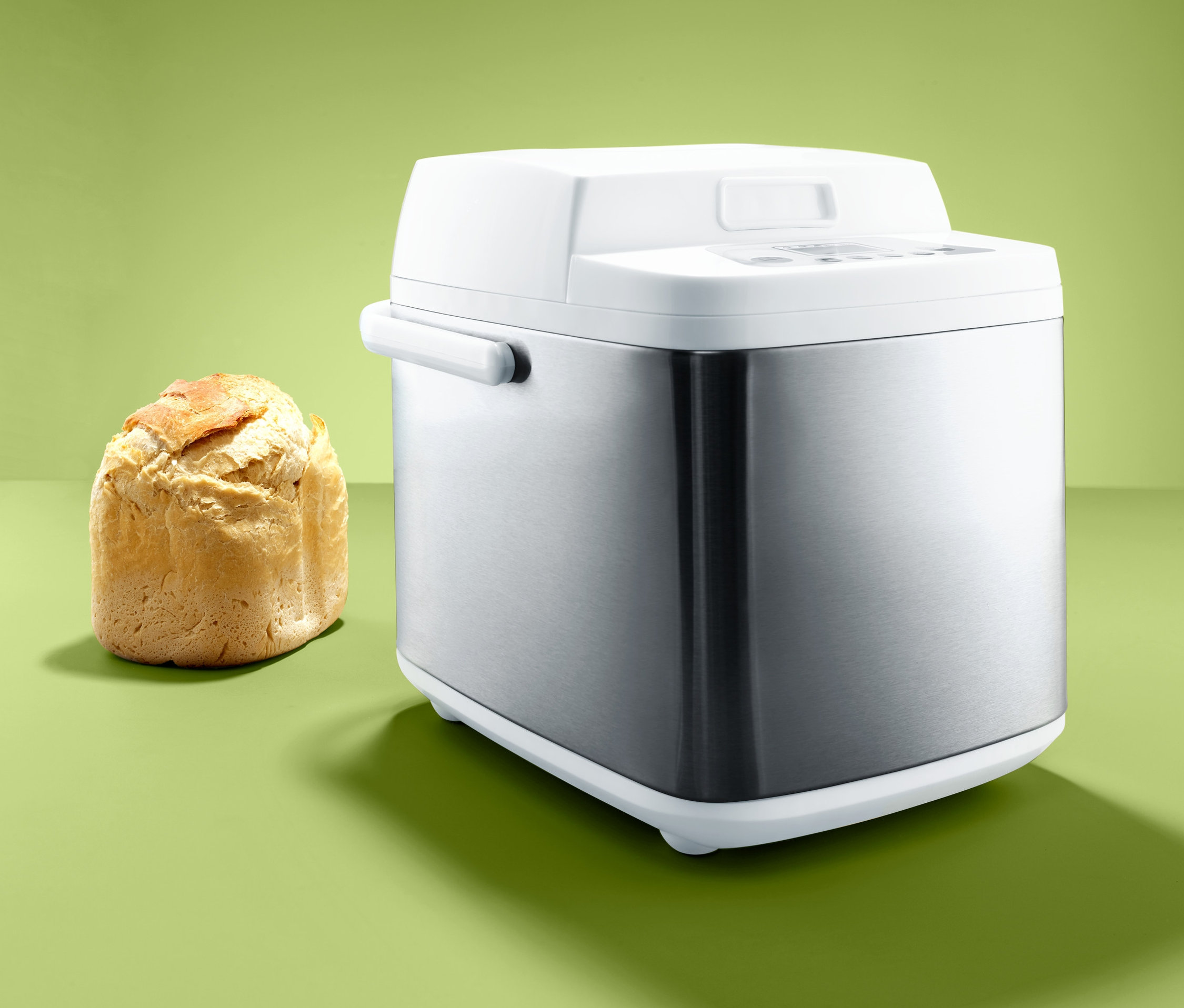 Ein Brotbackautomat steht neben einem gebackenen Brot.