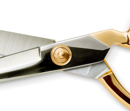 Detailaufnahme einer Profi-Schneiderschere mit silbernen Klingen und goldenen Griffen.