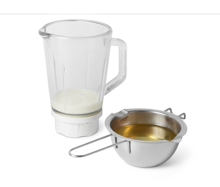 Ein Glasmixer mit Pflanzenmilch und eine Edelstahlschüssel mit Öl für das DIY-Pflanzenbutter-Set.