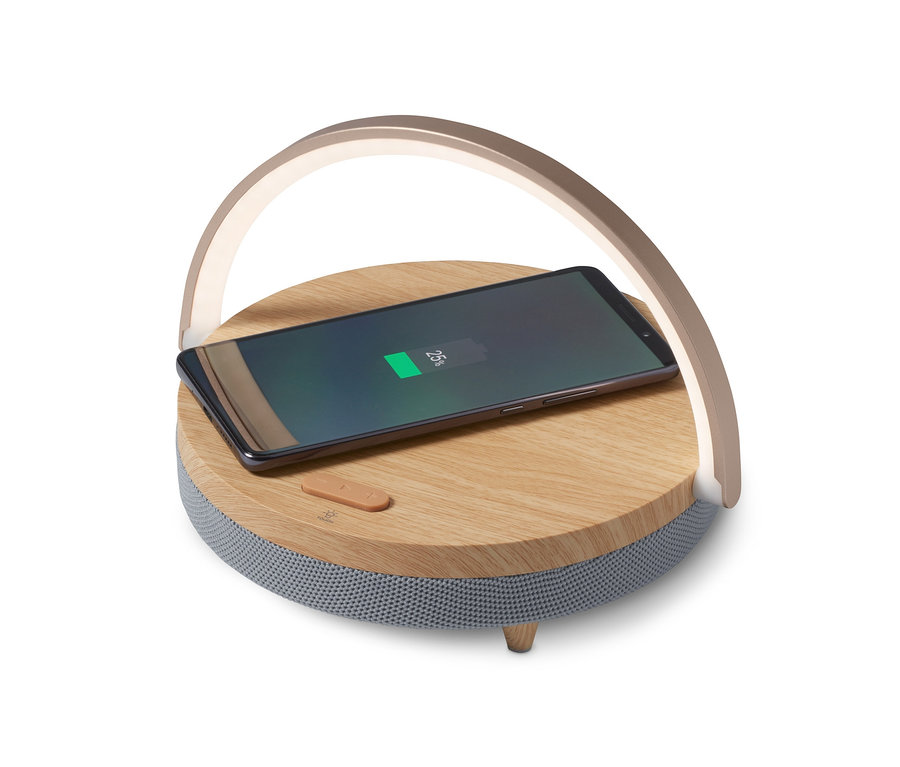 Ein Mobiltelefon lädt auf einem Bluetooth-Lautsprecher mit kabellosem Ladegerät und LED-Nachtlicht.