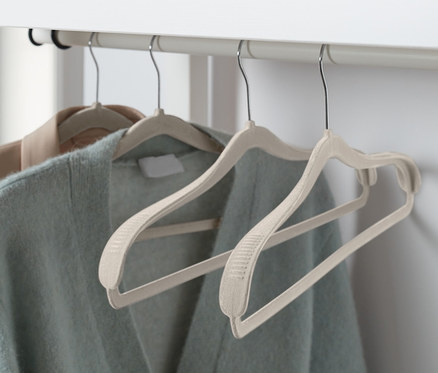 Zwei Pullover hängen an 4 Kleiderbügel mit Schulterverstärkung.